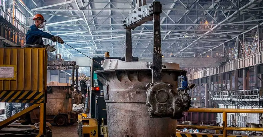 Aluminum smelting plant worker monitoring industrial equipment for real time SCADA and digital twin analytics