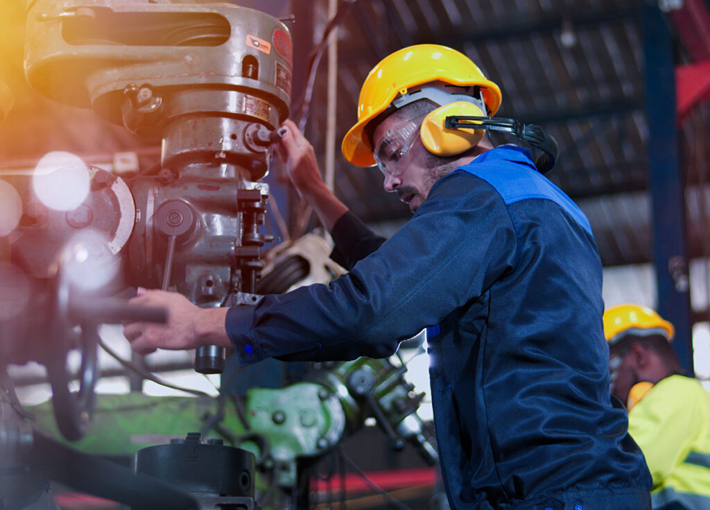 Industrial worker operating heavy machinery during live production shift in manufacturing plant