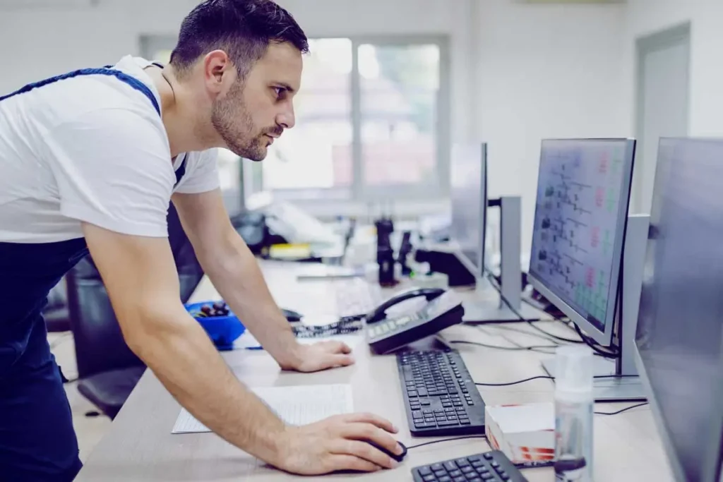 Industrial engineer monitoring real-time energy data and facility performance dashboards on control room screens