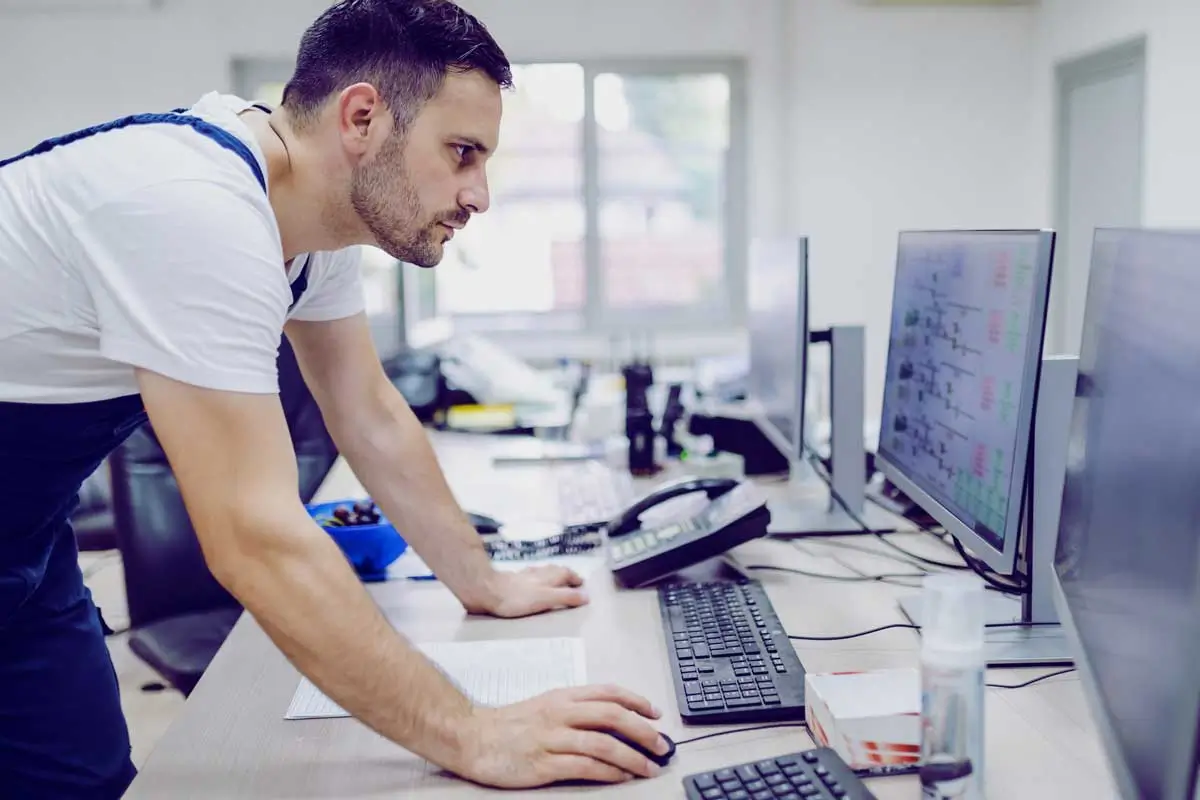 Industrial engineer monitoring real-time energy data and facility performance dashboards on control room screens